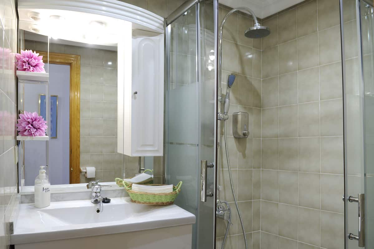 A modern bathroom with a glass-enclosed shower, a white sink, and a mirror above it.