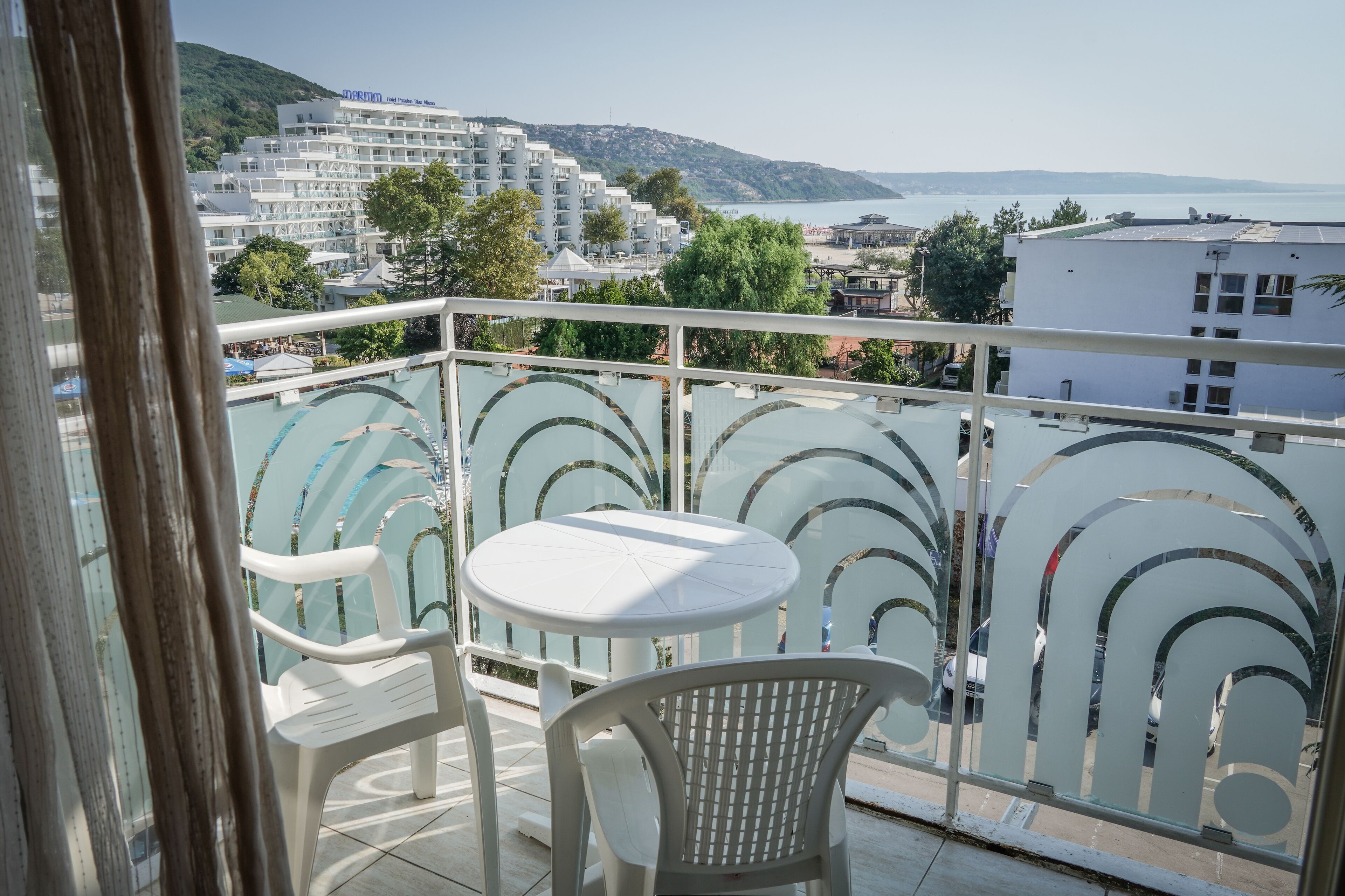 A balcony with a glass railing, a small table, and two chairs.