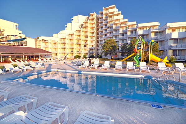Relax by the pool surrounded by lounge chairs and a children's play area.