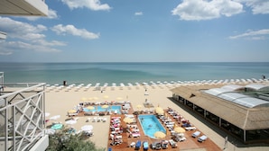 Un complexe hôtelier de bord de mer doté d’une piscine, de chaises longues, de parasols et offrant une vue sur la mer.