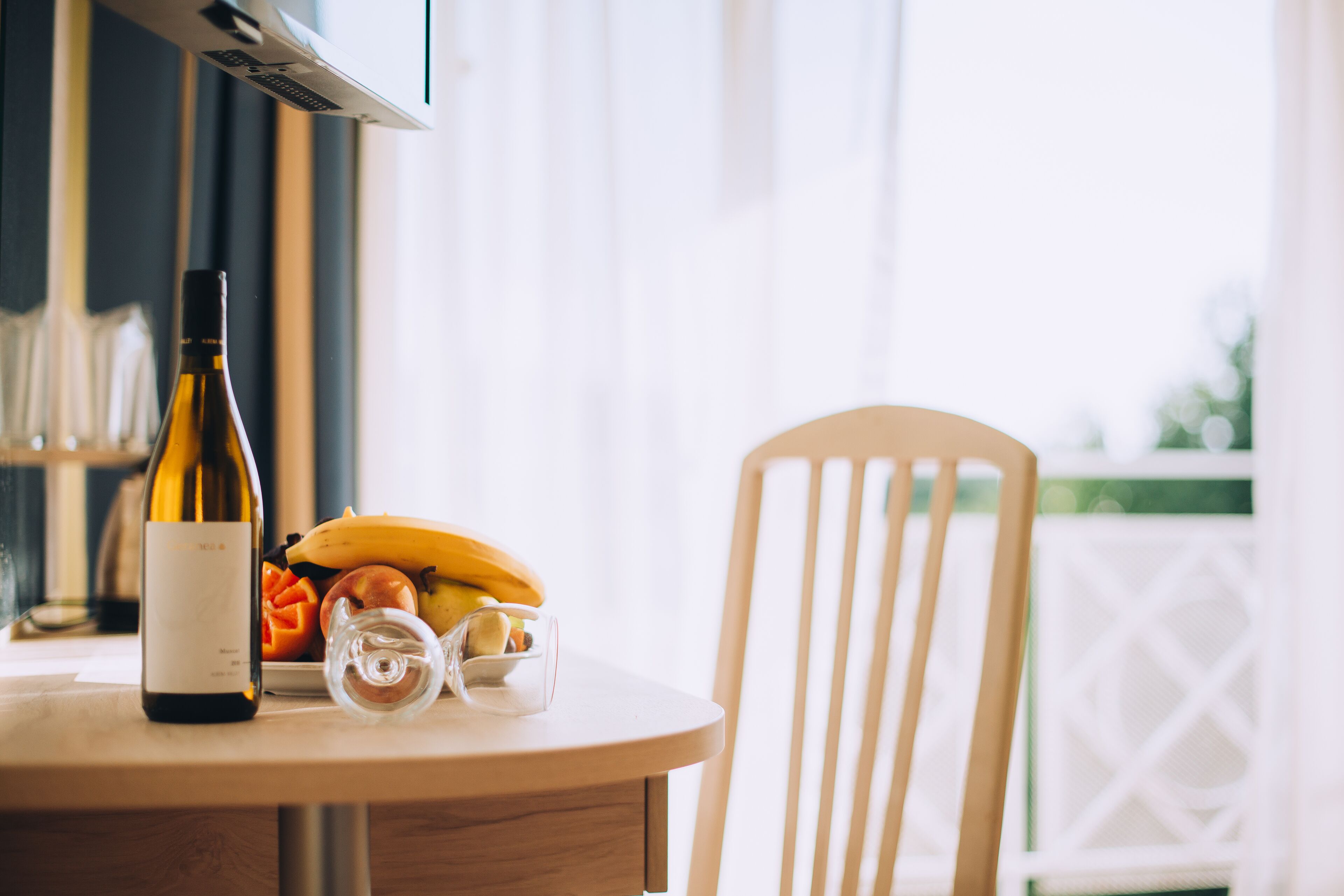 A table with a bottle of wine, a banana, and a glass on a wooden table.
