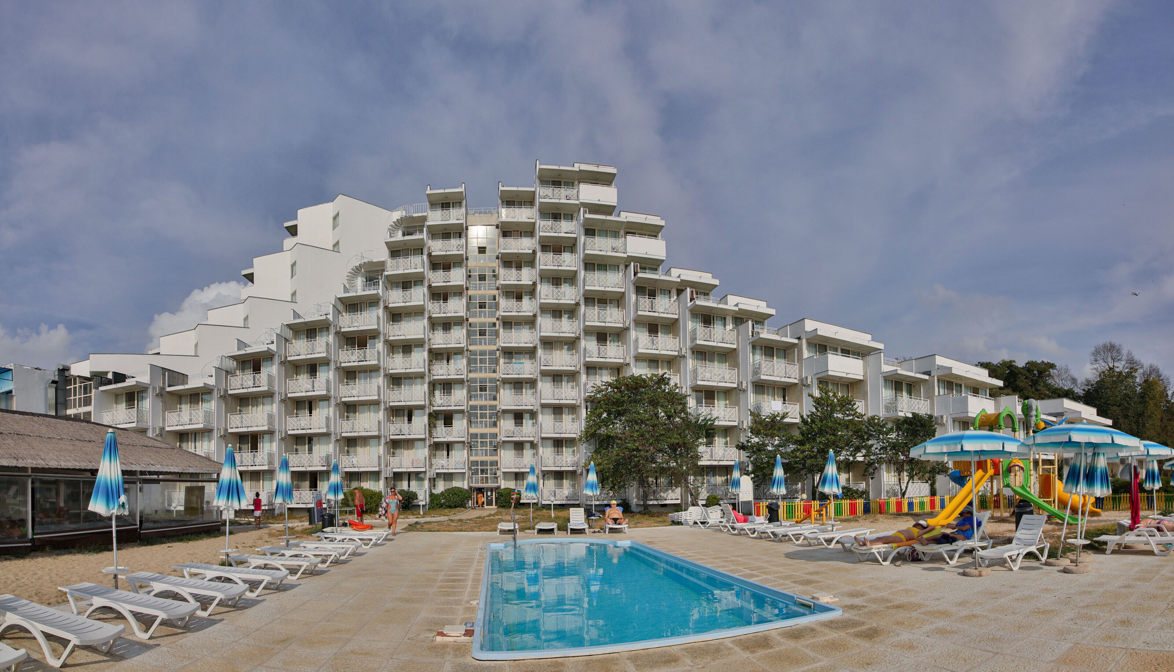 A hotel with a large pool, multiple balconies, and outdoor seating areas.