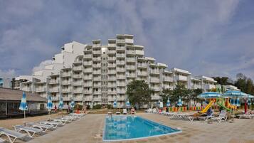 A hotel with a large pool, multiple balconies, and outdoor seating areas.