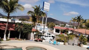 A hotel named 'Hotel Marina' with a signboard, a swimming pool, and a mountainous backdrop. - Hotel Marina Topolobampo (Topolobampo)