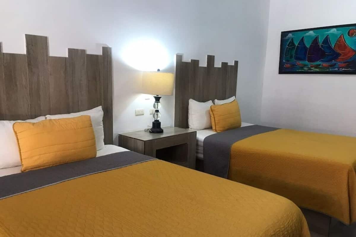 A hotel room with two beds, a nightstand with a lamp, and a painting on the wall.