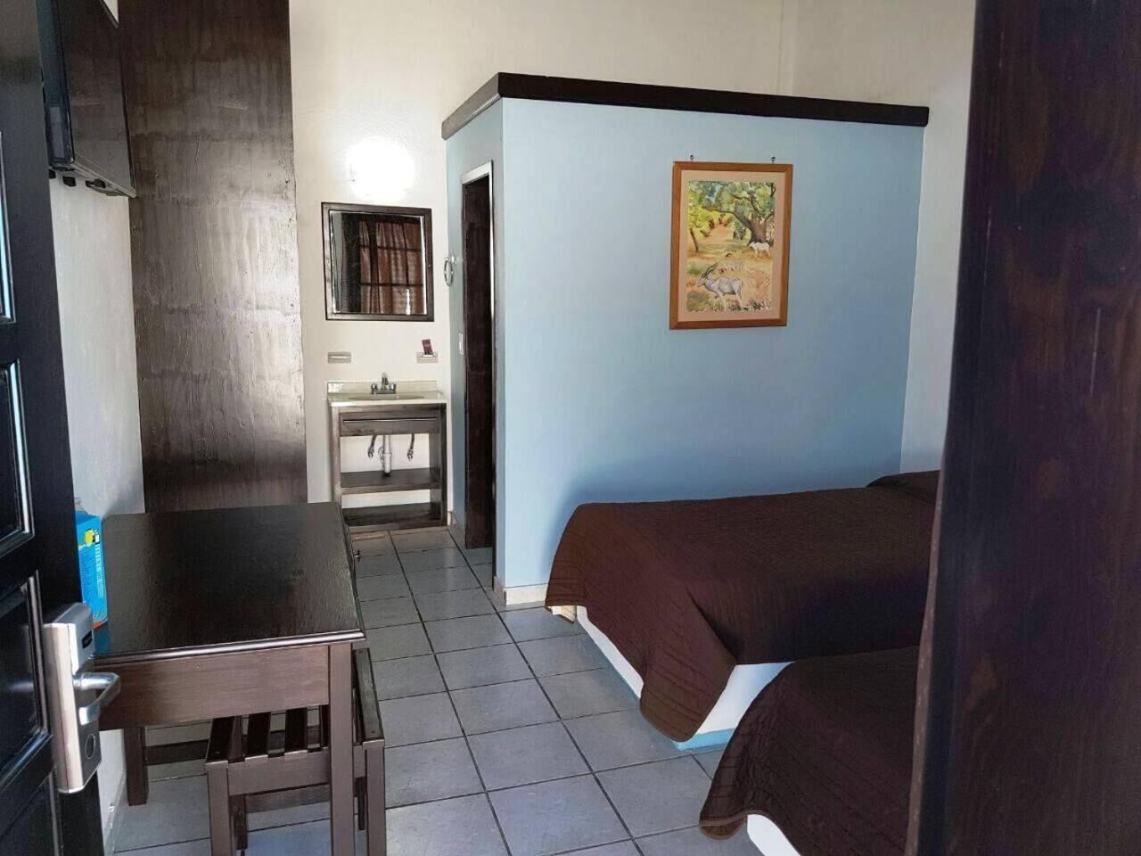 Une pièce comprenant un lit, une table, un lavabo et une fenêtre.