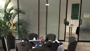 A dining area with tables set for a meal, chairs, a vase of flowers, and a view of the outside through glass doors. - Hotel Marina Topolobampo (Topolobampo)