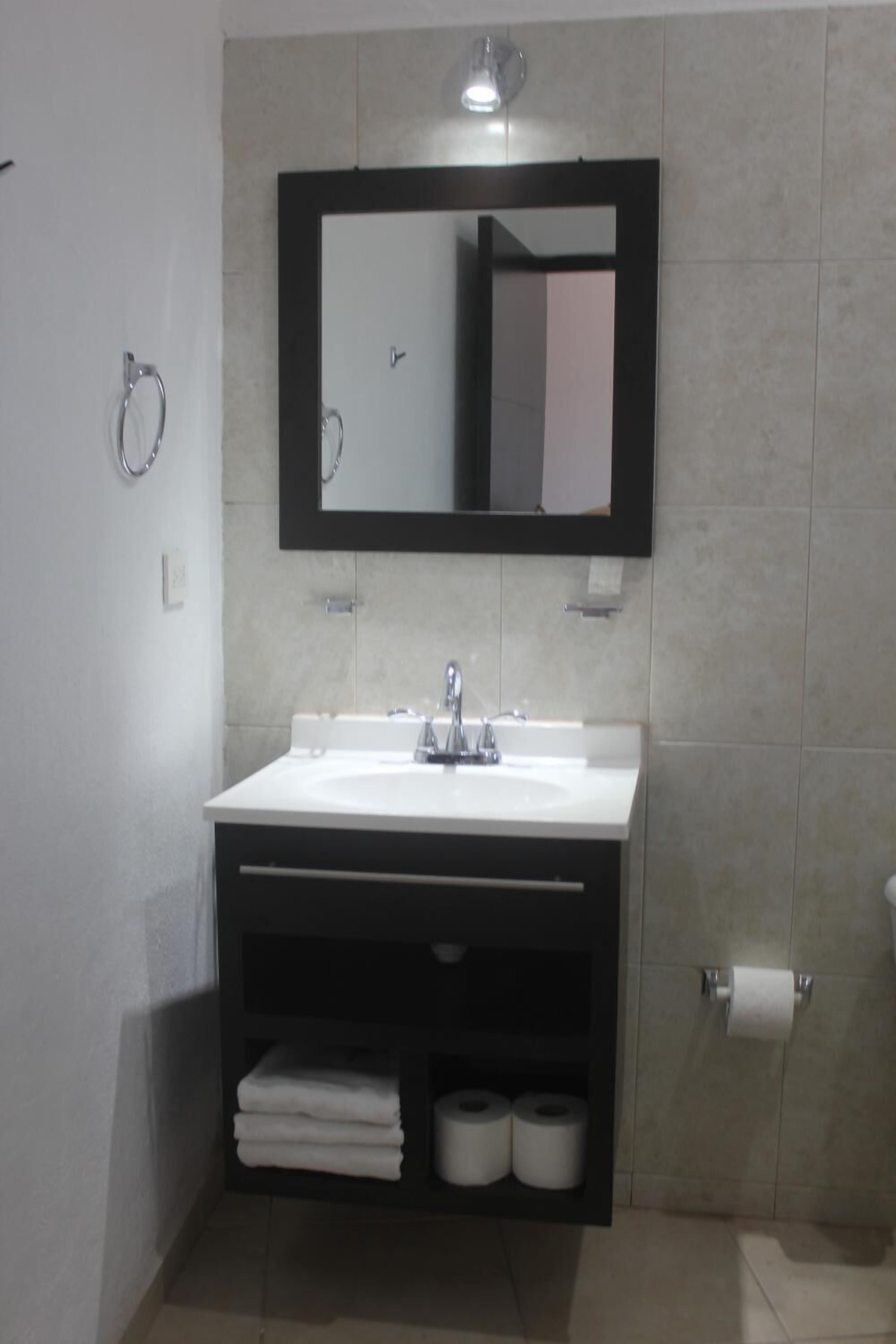 Uma casa de banho moderna com uma sanita, um lavatório branco e um espelho.