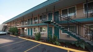 A motel with a two-story structure, a parking lot, and a staircase leading to the upper floor. - Executive Motel (Eugene)