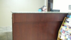 A wooden counter with a tiled floor and a magazine rack to the right. - Executive Motel (Eugene)