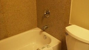 A bathroom with a bathtub, toilet, and a towel hanging on the wall. - Executive Motel (Eugene)
