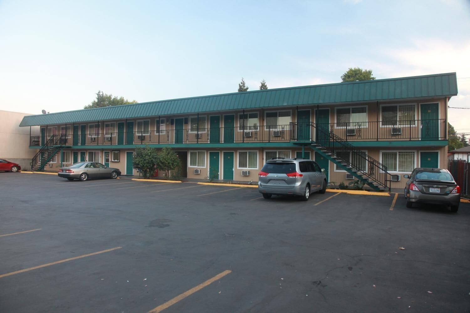 A motel with a two-story structure, a parking lot, and several cars parked in front.