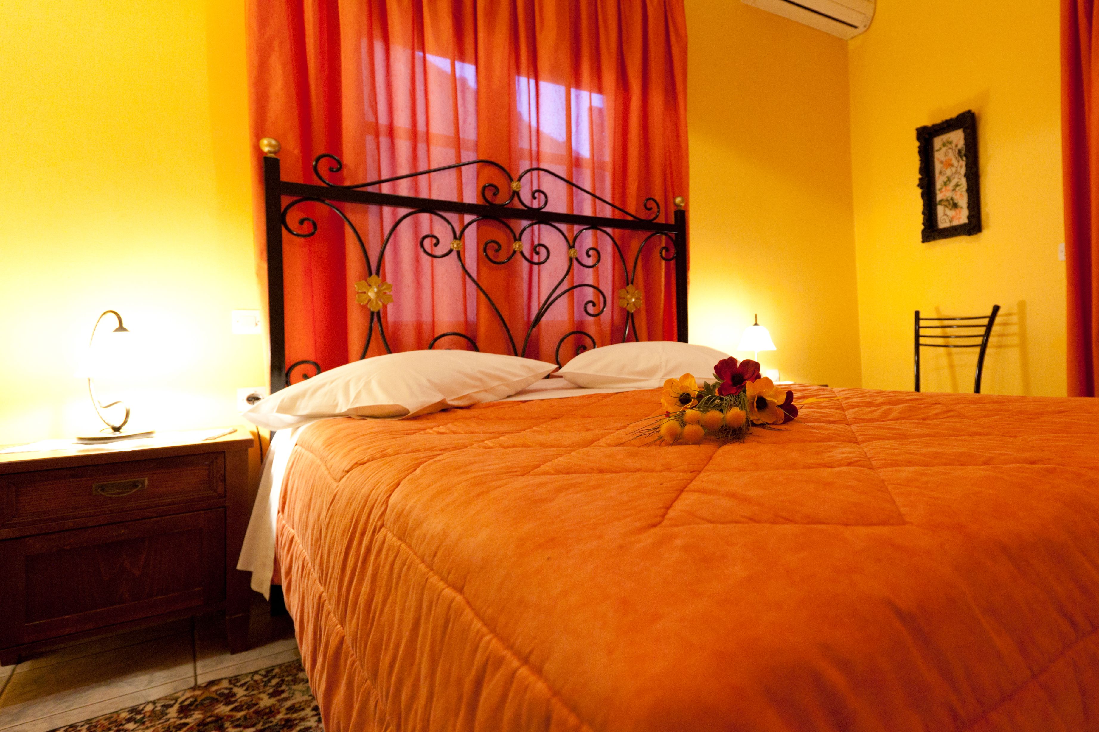 A hotel room with a bed, a nightstand, a lamp, and a chair.