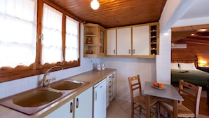 A compact kitchen with wooden cabinets, a sink, and a dining area with a table and chairs.