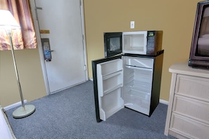 A compact room with a refrigerator, a microwave, a television, and a door with a sign. - Travelodge by Wyndham Phoenix Downtown (Phoenix)