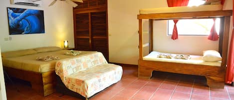 A room with two beds, a ceiling fan, and a window with red curtains.