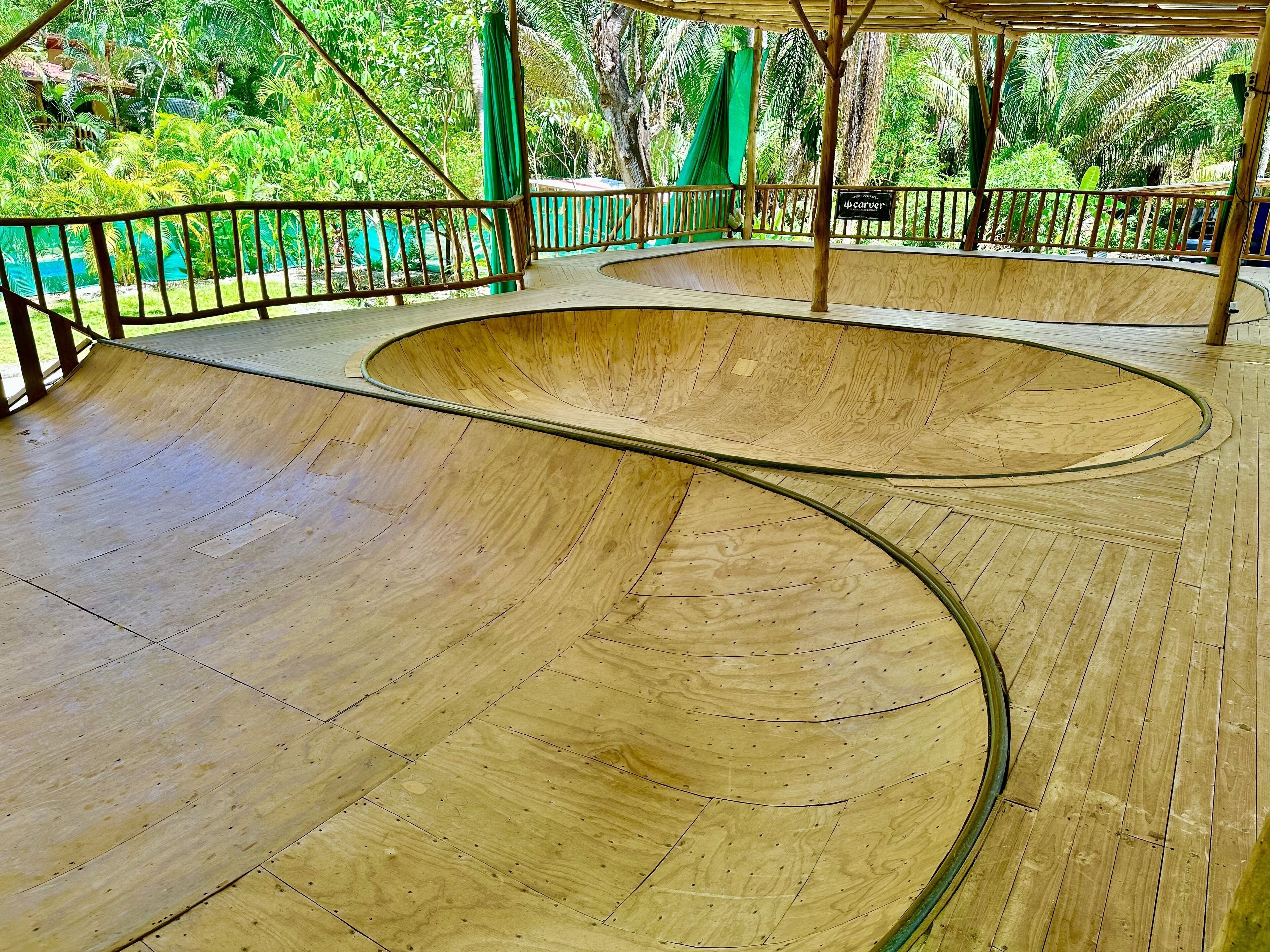 Uma pista de skate de madeira com uma rampa curva e área cercada.