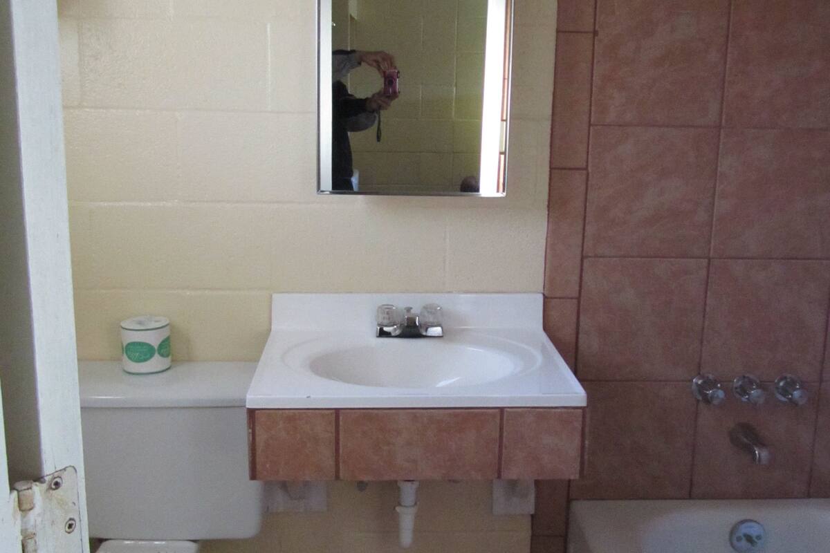 Un baño pequeño con lavamanos blanco, espejo, inodoro y bañera.