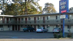 A motel with a sign indicating vacancies. It has a two-story structure with a balcony on the upper floor. There are several cars parked in front, and the date is 10.14.2013. - Relax Inn (Cottage Grove)