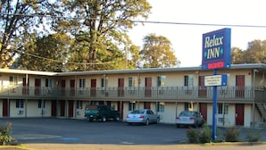 A two-story motel with a sign reading "Relax Inn" and a sign indicating "Commercial, Senior, Daily and Weekly Rates." - Relax Inn (Cottage Grove)