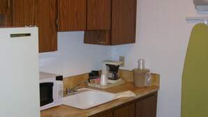 A kitchen with wooden cabinets, a white sink, a microwave, a coffee maker, and a blender. - Shanico Inn (Lebanon)