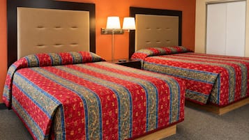 Una habitación de hotel con dos camas, una mesita de noche, una lámpara y una puerta.