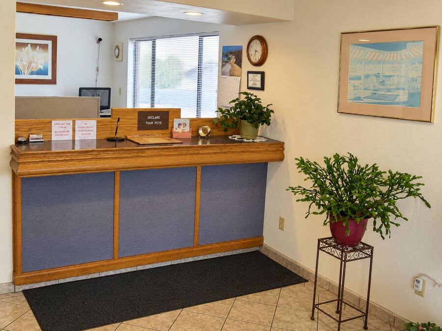 A reception desk with a check-out time sign, a clock, and a framed picture on the wall.