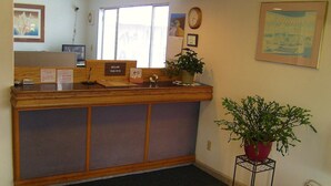 A reception desk with a check-out counter, a clock, and a framed picture on the wall. - Shanico Inn (Lebanon)