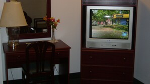 A wooden desk with a lamp, a vase with flowers, and a television on a stand. - Shanico Inn (Lebanon)