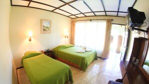 A hotel room with two beds, a desk, a television, and a window with curtains. - Hotel Wagelia Turrialba (Turrialba)