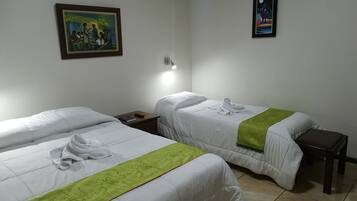 A hotel room with two beds, a nightstand, a painting, and a poster on the wall.