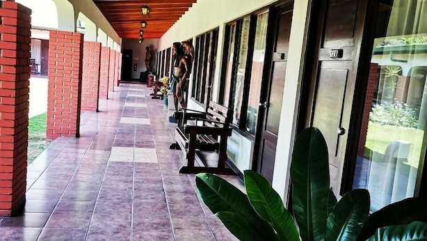 A covered corridor with tiled flooring, benches, and large windows. - Hotel Wagelia Turrialba (Turrialba)