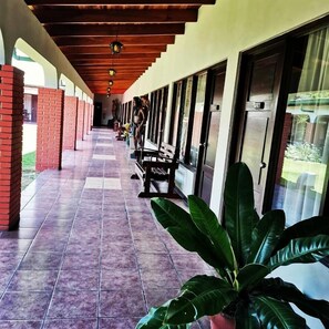 A covered corridor with tiled flooring, benches, and large windows. - Hotel Wagelia Turrialba (Turrialba)