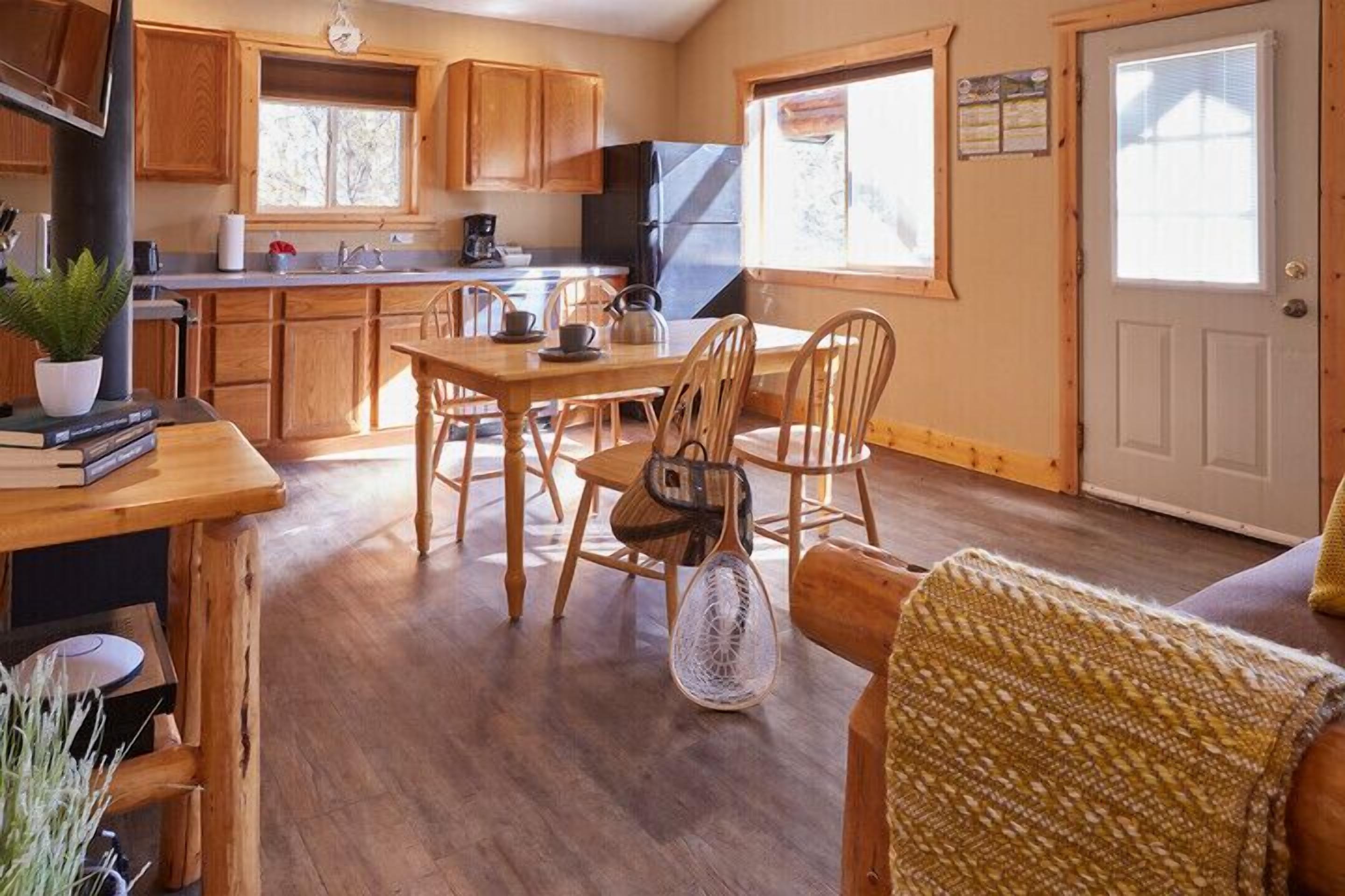 A cozy kitchen with wooden cabinets, a dining table with chairs, and a window providing natural light.