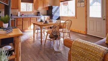 A cozy kitchen with wooden cabinets, a dining table with chairs, and a window providing natural light.