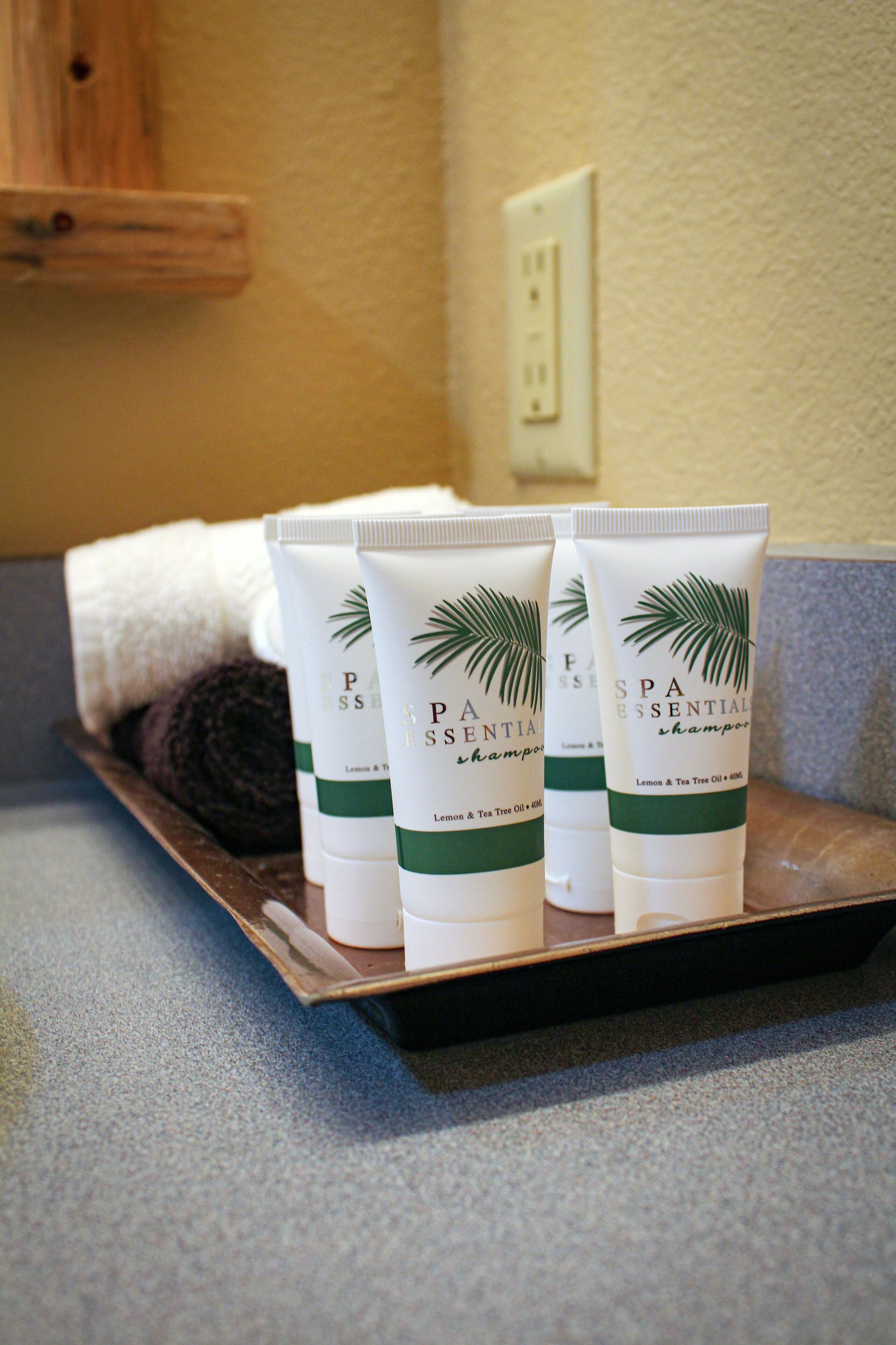 Drei Flaschen SPA ESSENTIAL Shampoo auf einer Ablagefläche.