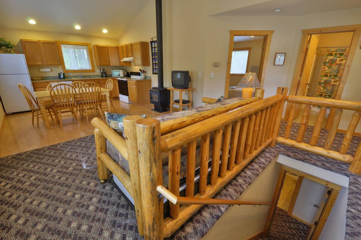 A cozy kitchen with wooden cabinets, a dining area with chairs, a TV, and a fireplace.