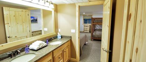 A bathroom with a large mirror, two sinks, and wooden cabinets.