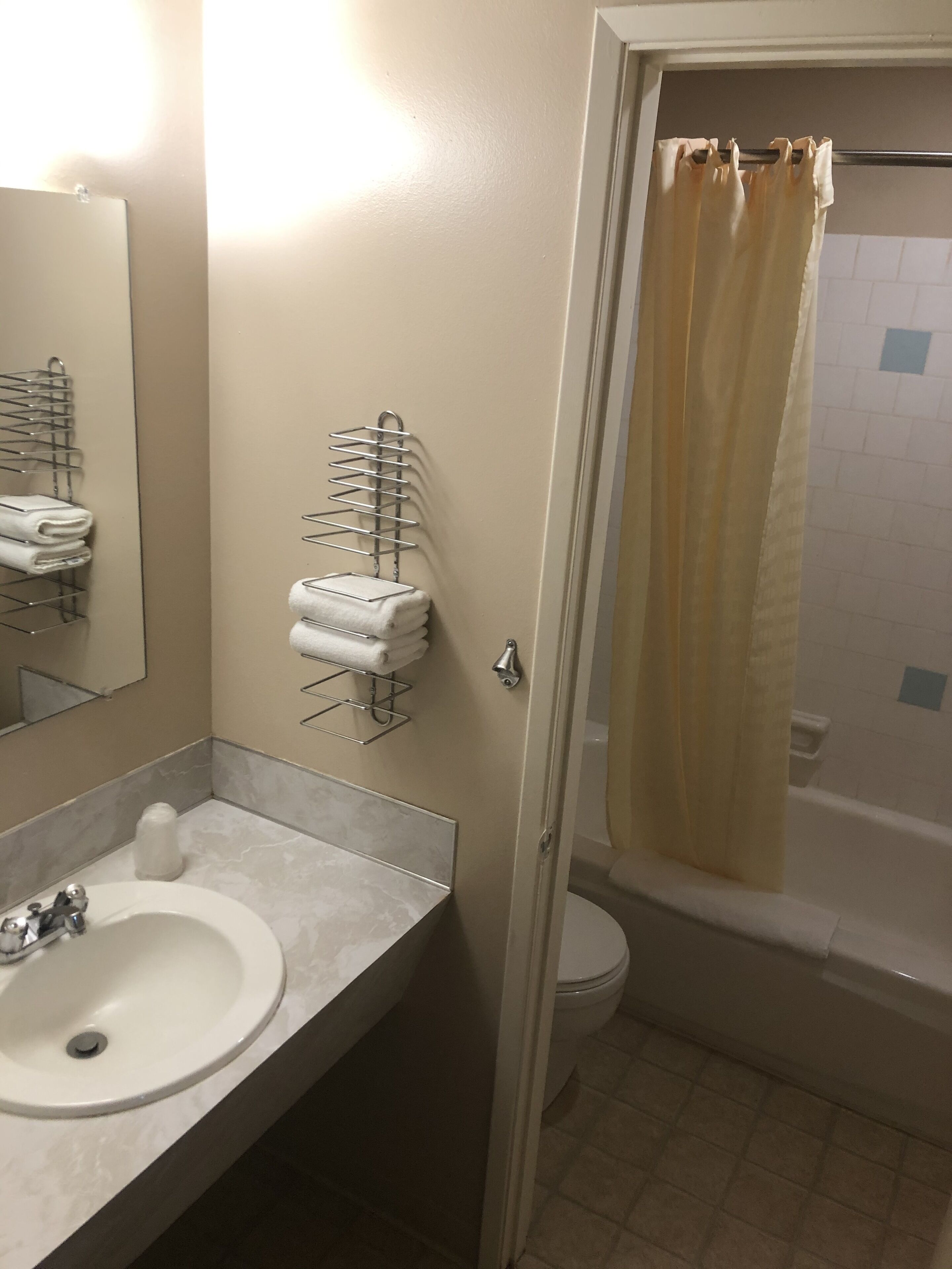 Un baño con lavabo, espejo, toallero y cortina de ducha.