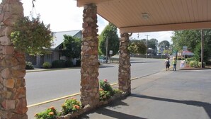 A covered parking area with stone pillars and flower beds. - Riverside Inn Dallas (Dallas)