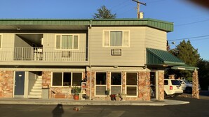 A two-story building with a green roof, a balcony on the upper floor, and a small front porch with potted plants. - Riverside Inn Dallas (Dallas)