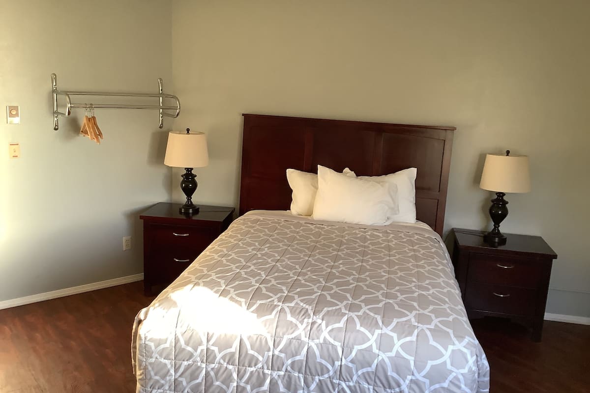 A neatly made bed with a patterned bedspread, two bedside tables with lamps, and a wooden headboard.