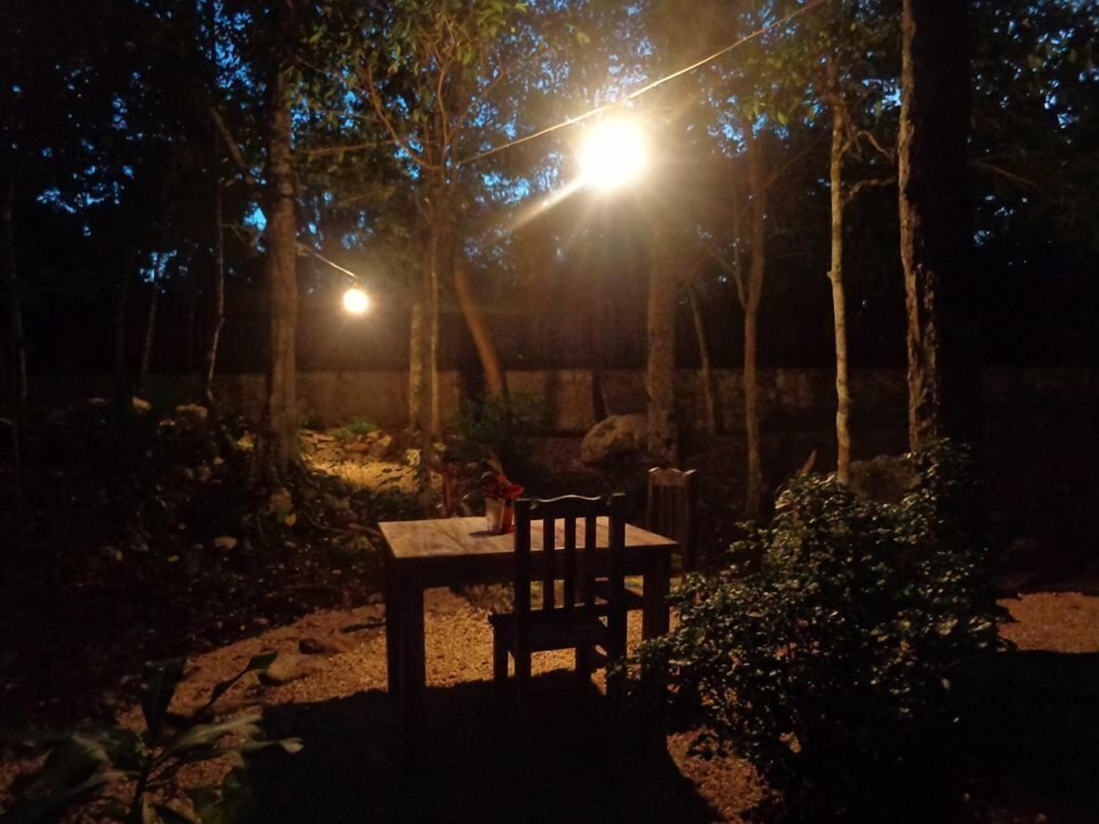 A table and chairs set outdoors at night with string lights overhead.