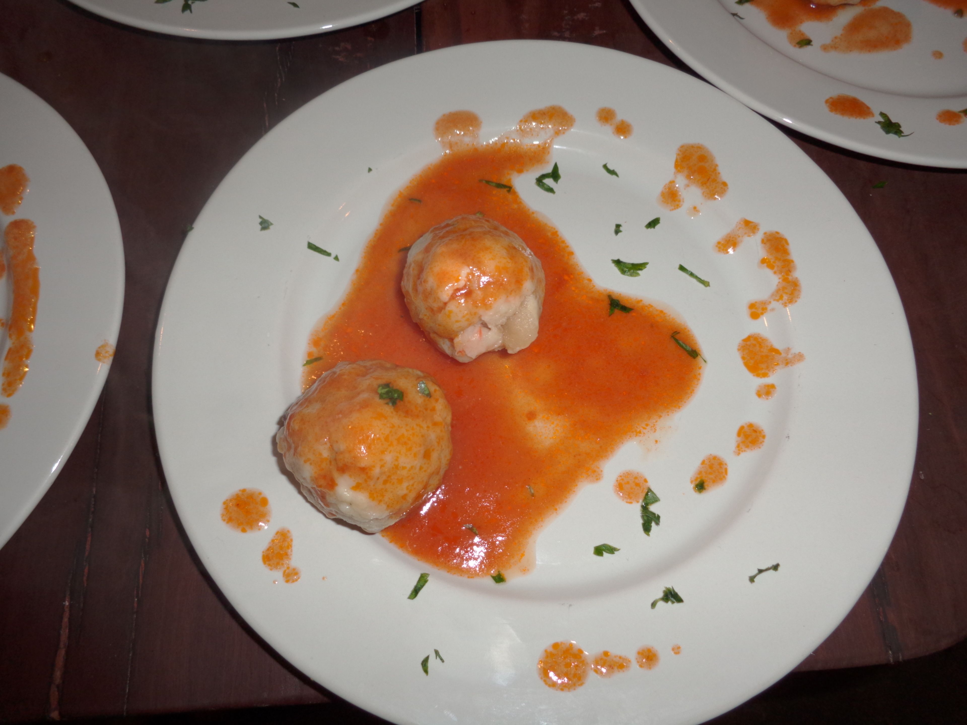 Un piatto con due gnocchi in salsa di pomodoro, guarnito con erbe aromatiche.