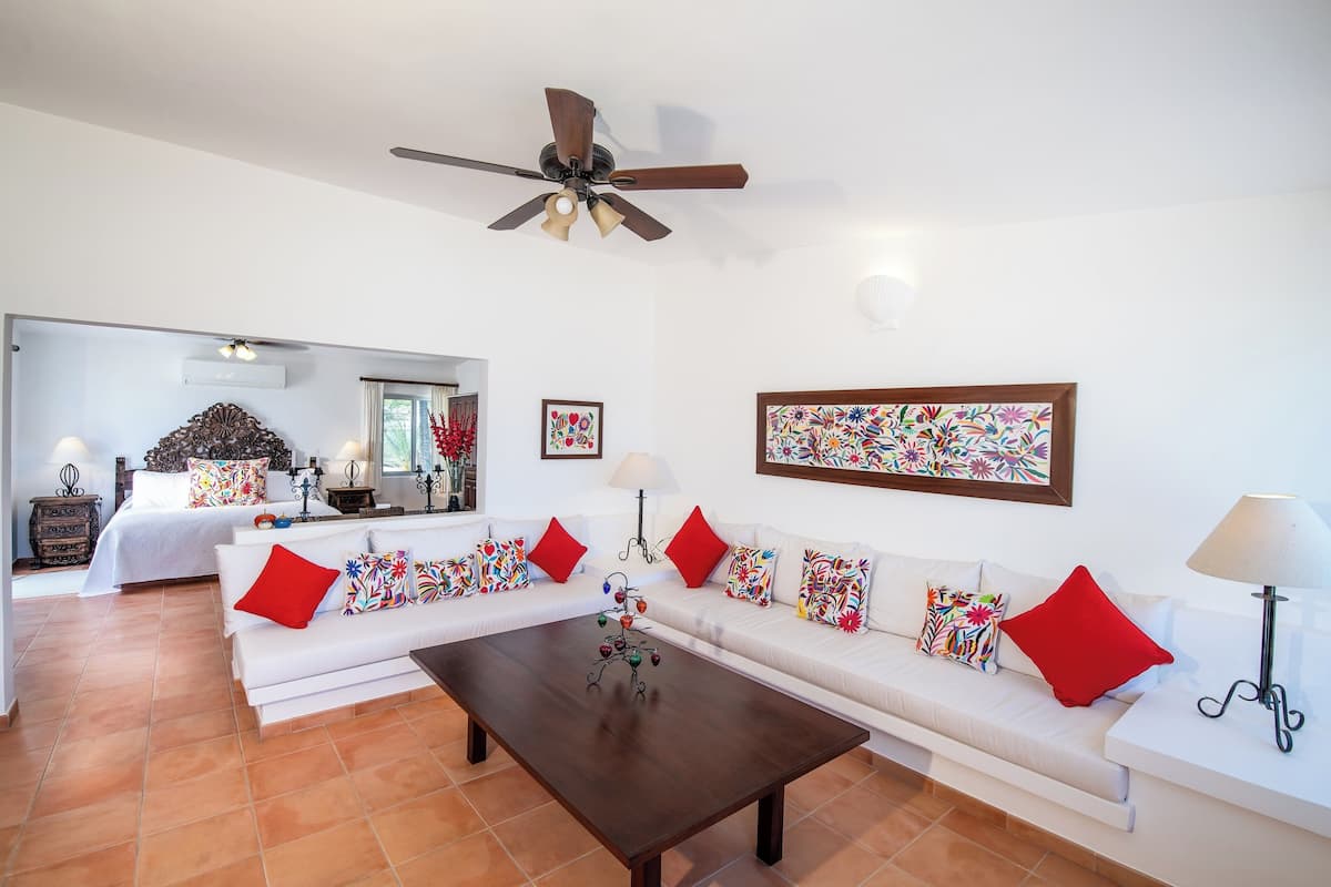 A modern living room with a sofa set, a coffee table, and a ceiling fan.
