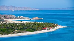 A coastal landscape with a beach, a small island with buildings, and a mountainous background. - Rancho Las Cruces Baja California Sur (Las Cruces)