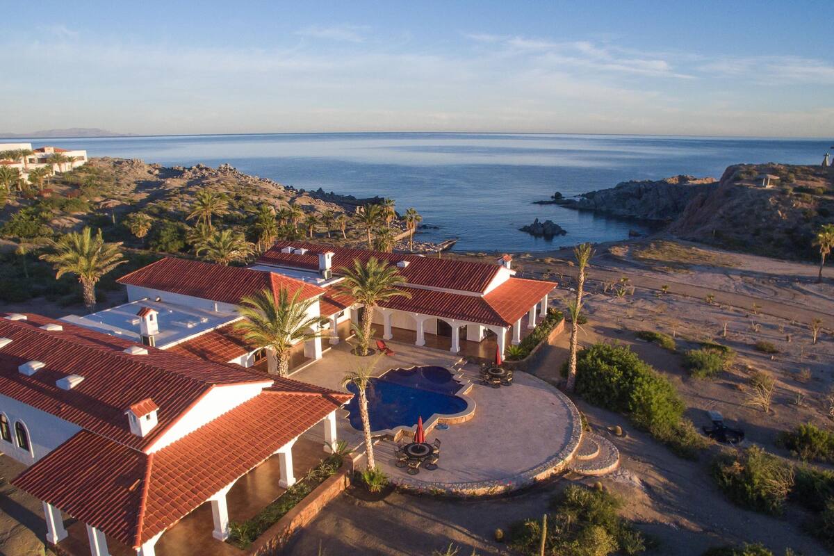 A coastal property with multiple buildings, a swimming pool, and a view of the sea.