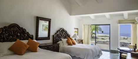 A hotel room with two beds, a desk, and a view of the beach.