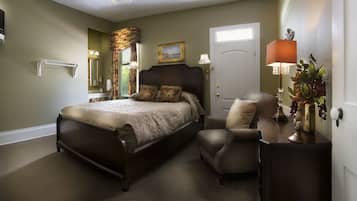 A bedroom with a bed, a chair, a nightstand, a lamp, a door, and a window.