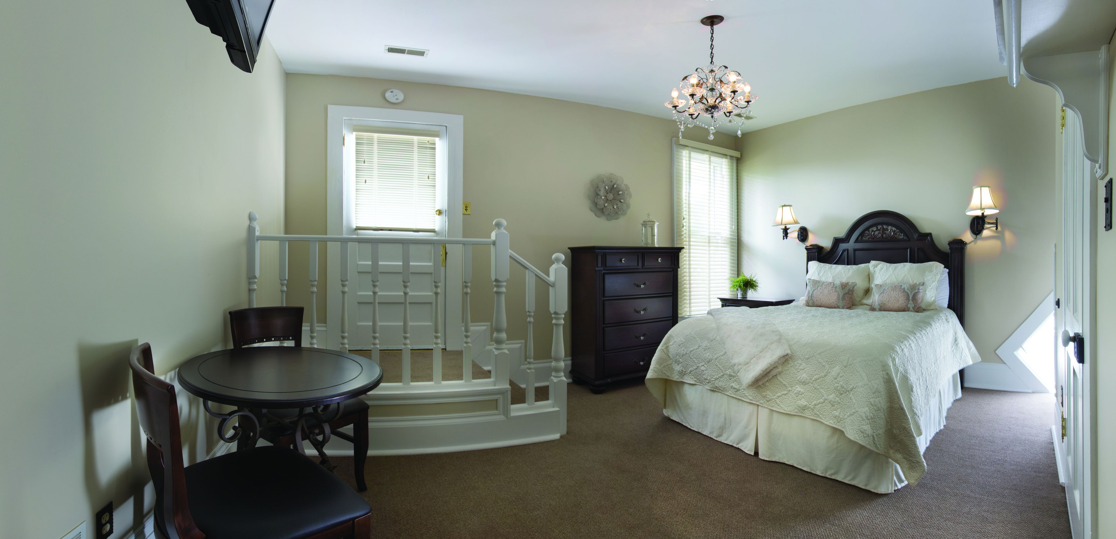Un dormitorio con cama, cómoda, silla, mesa y escalera.